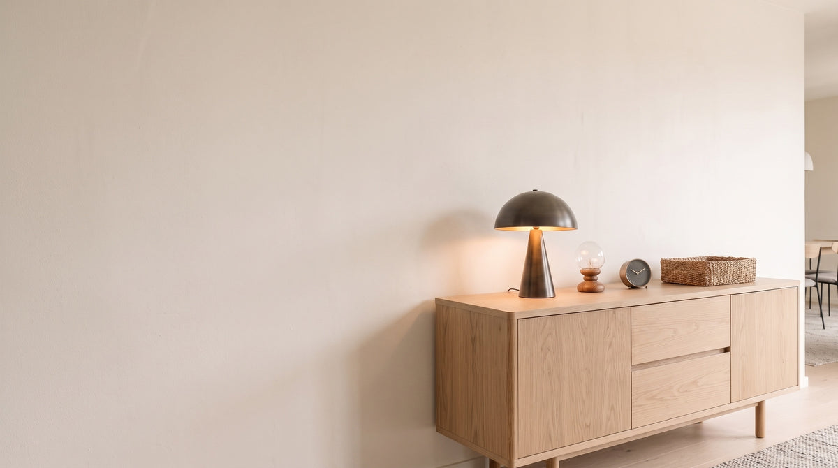 Table lamp, glass ball lamp, clock and woven basket on an oak sideboard